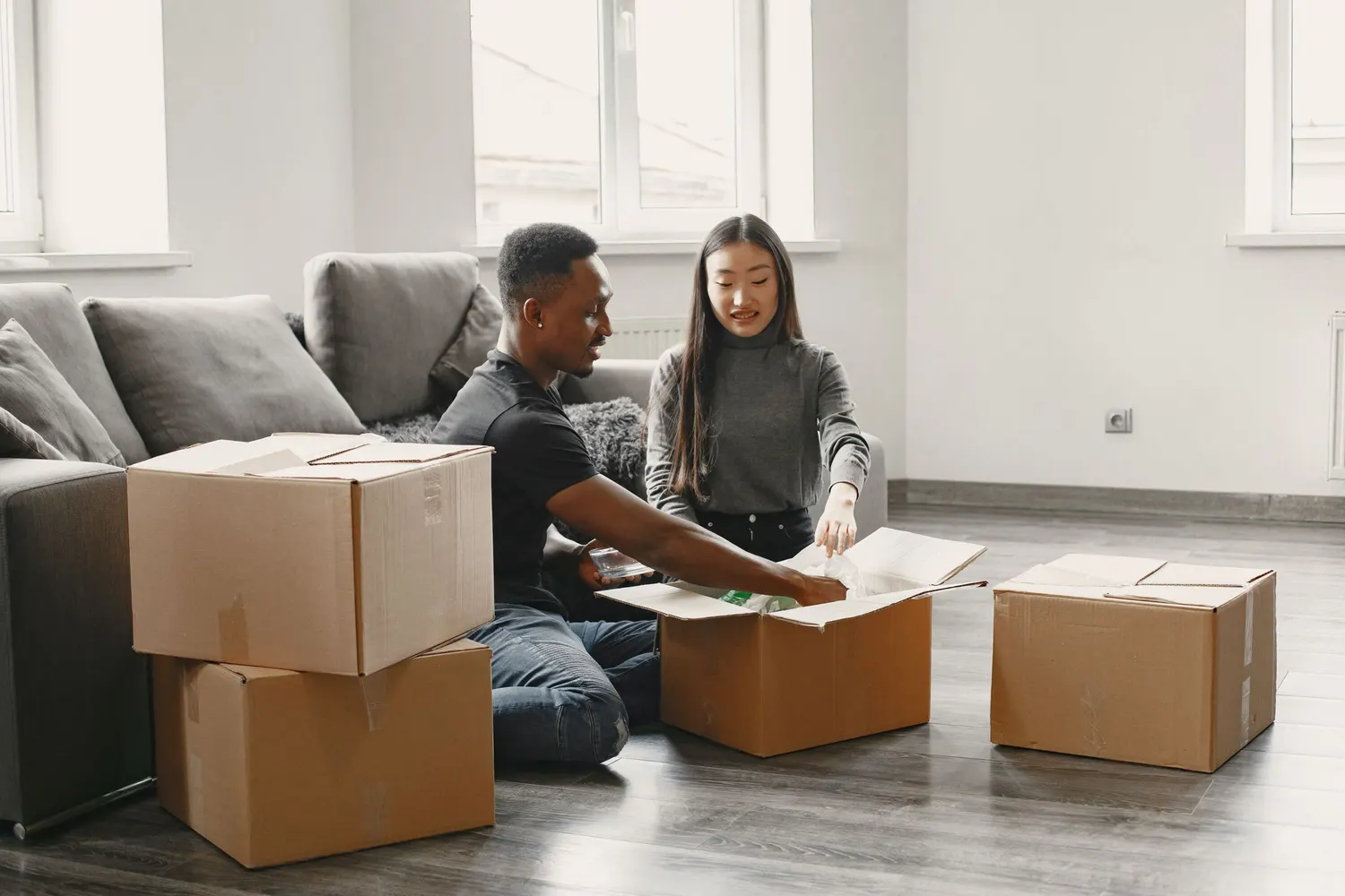 A couple unpacking moving boxes in a bright, half-furnished flat