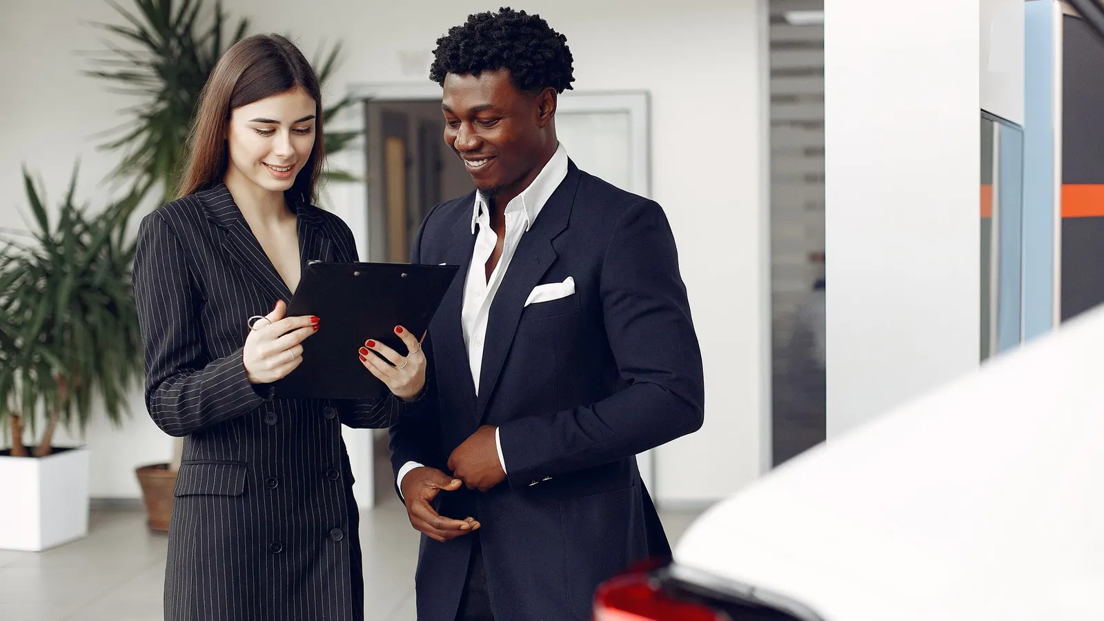 A car dealer and a customer reading a document in a showroom